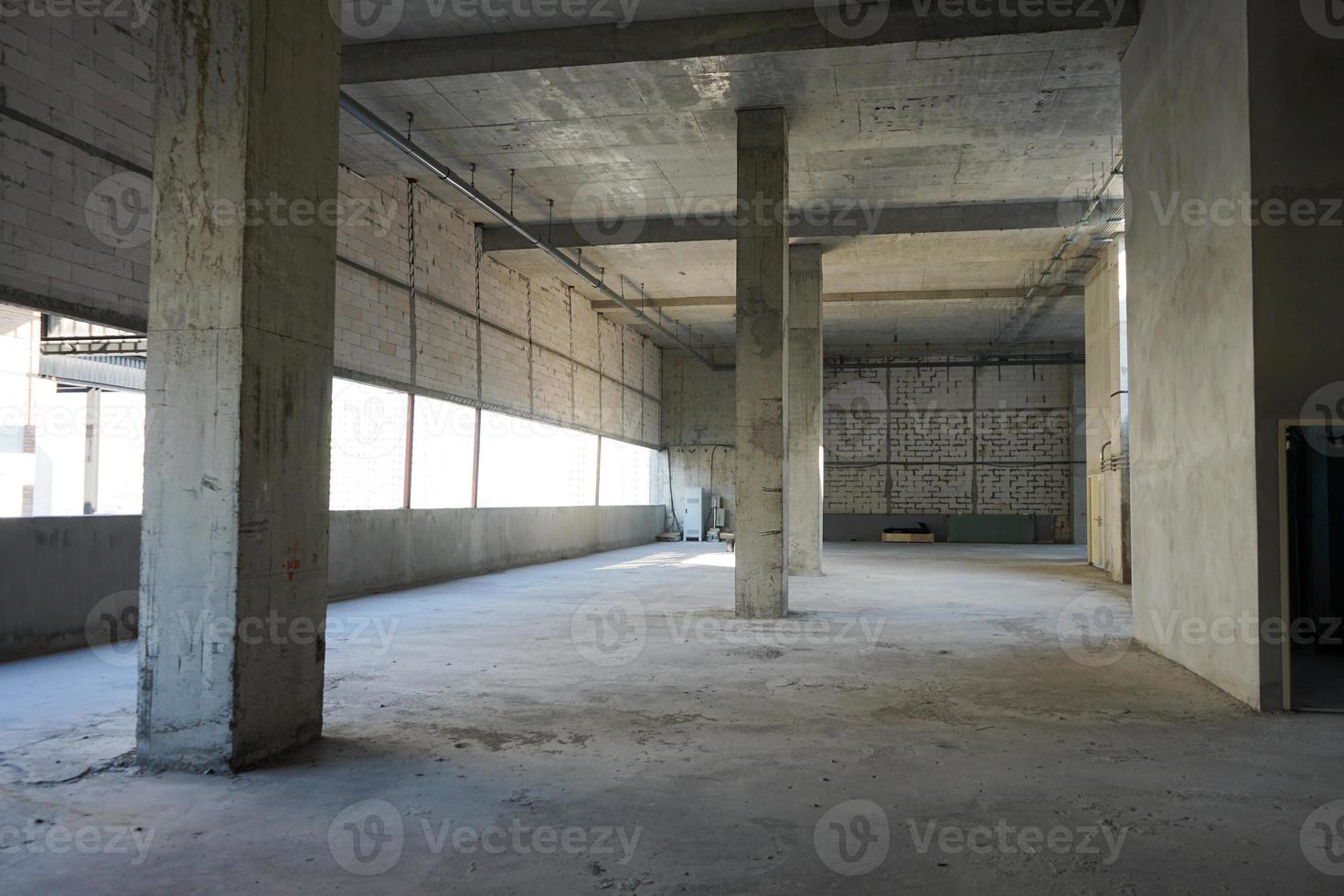 Under construction loft and raw brick rooftop at the large building with poles and tube on the ceiling. photo