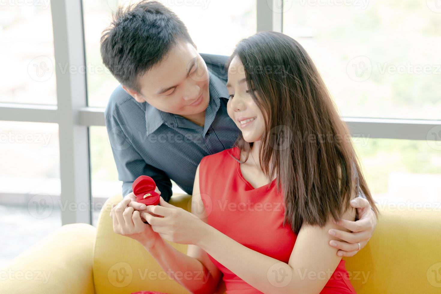 Happy young woman receiving engagement ring from her boyfriend photo