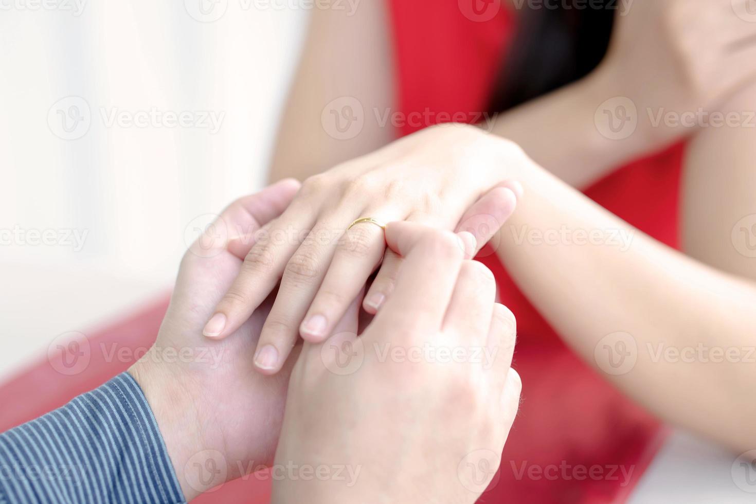 Close up of man putting wedding ring on woman finger photo
