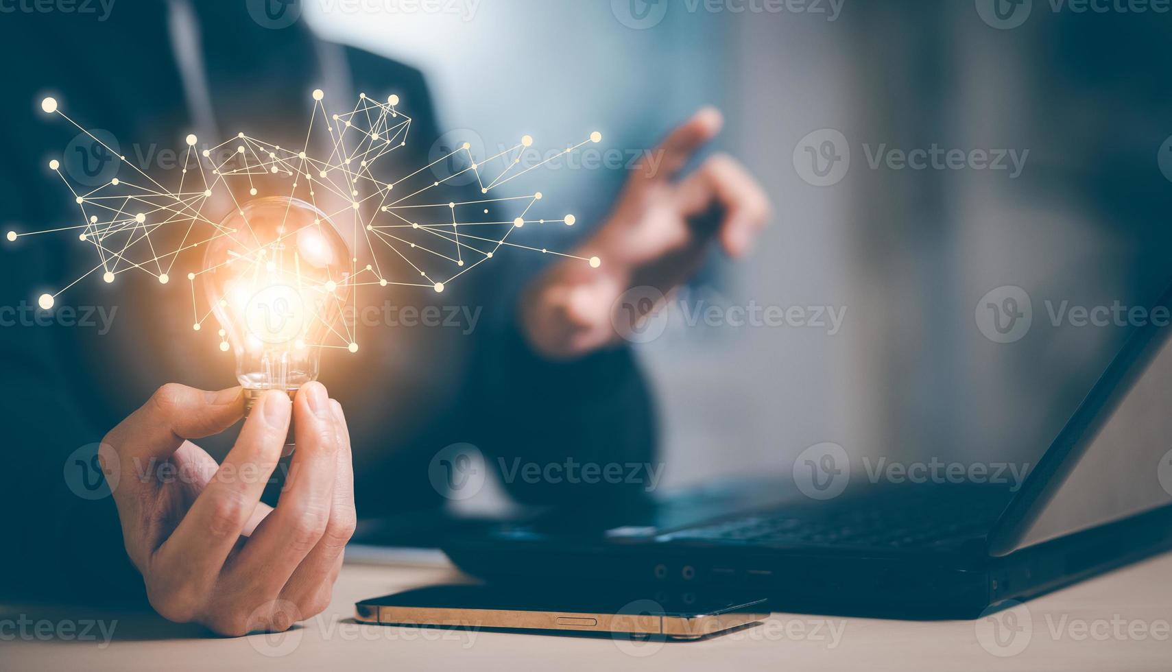 Businessman hand holding light bulb with icons and working on the desk, Creativity and innovation are keys to success.Concept of new idea and innovation with energy and power , working at home, photo