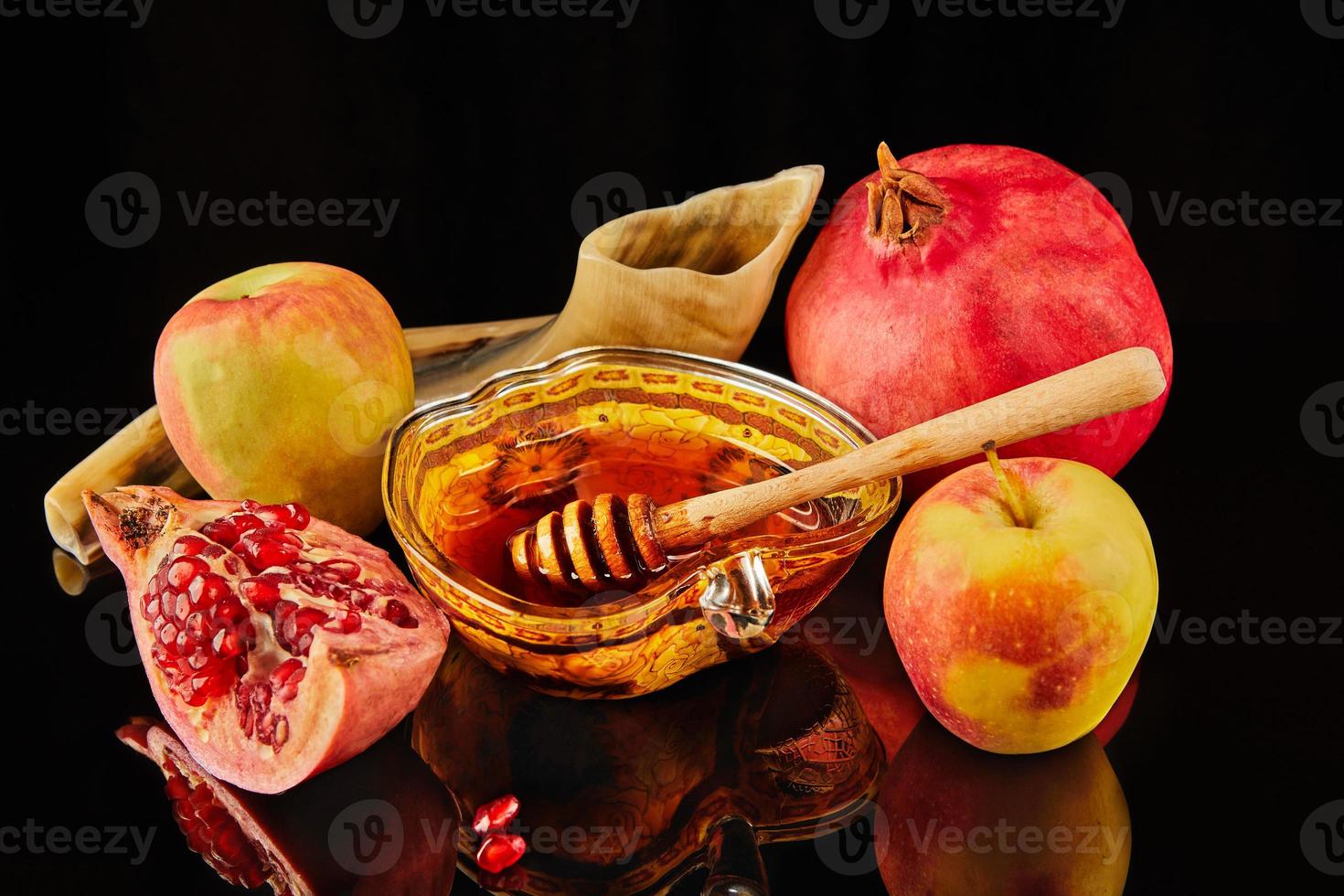 Rosh hashanah - jewish new year holiday concept. Apple-shaped bowl with honey, apples, pomegranates, shofar on black background with reflection photo