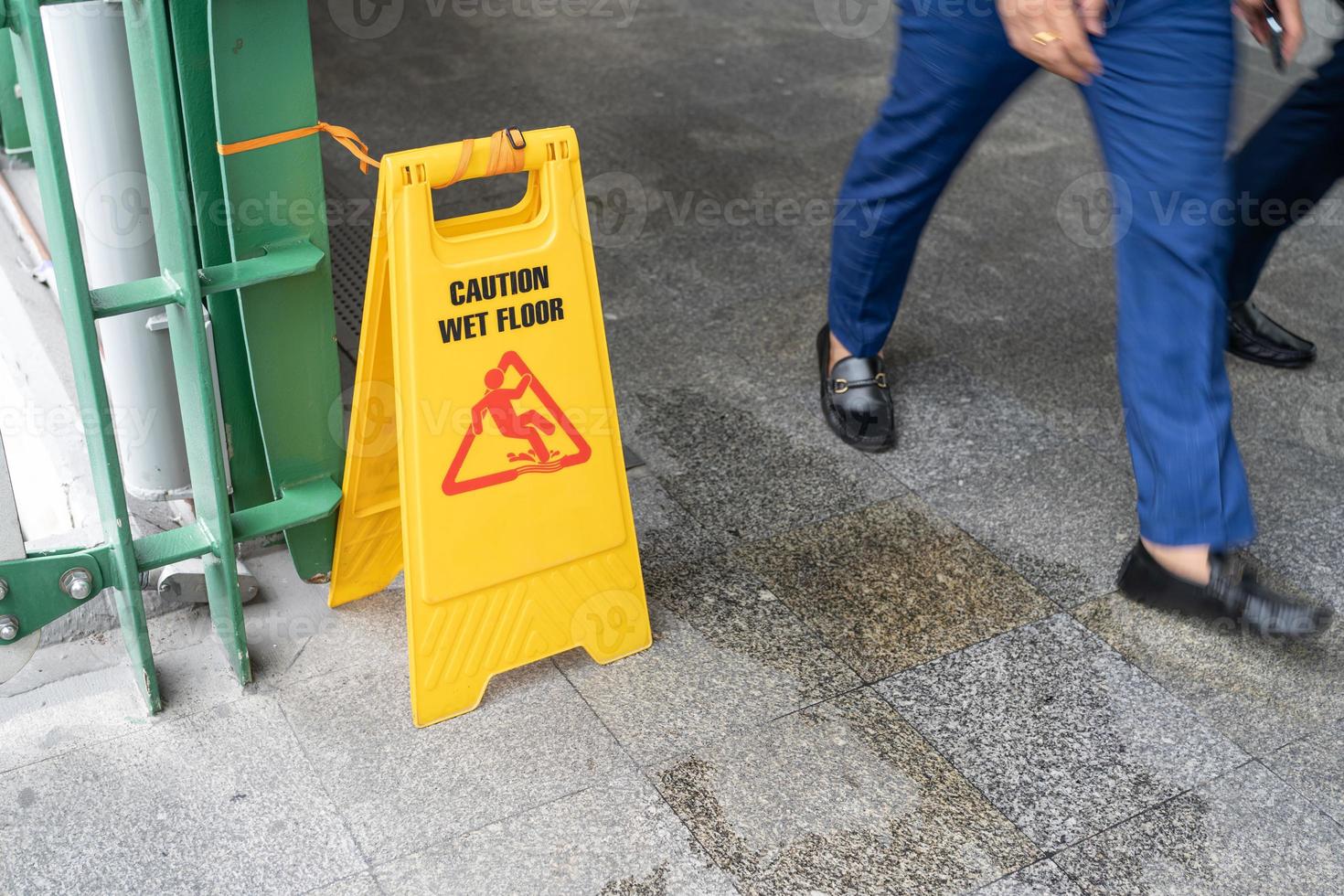 Yellow Caution slippery wet floor sign on the wet ground photo