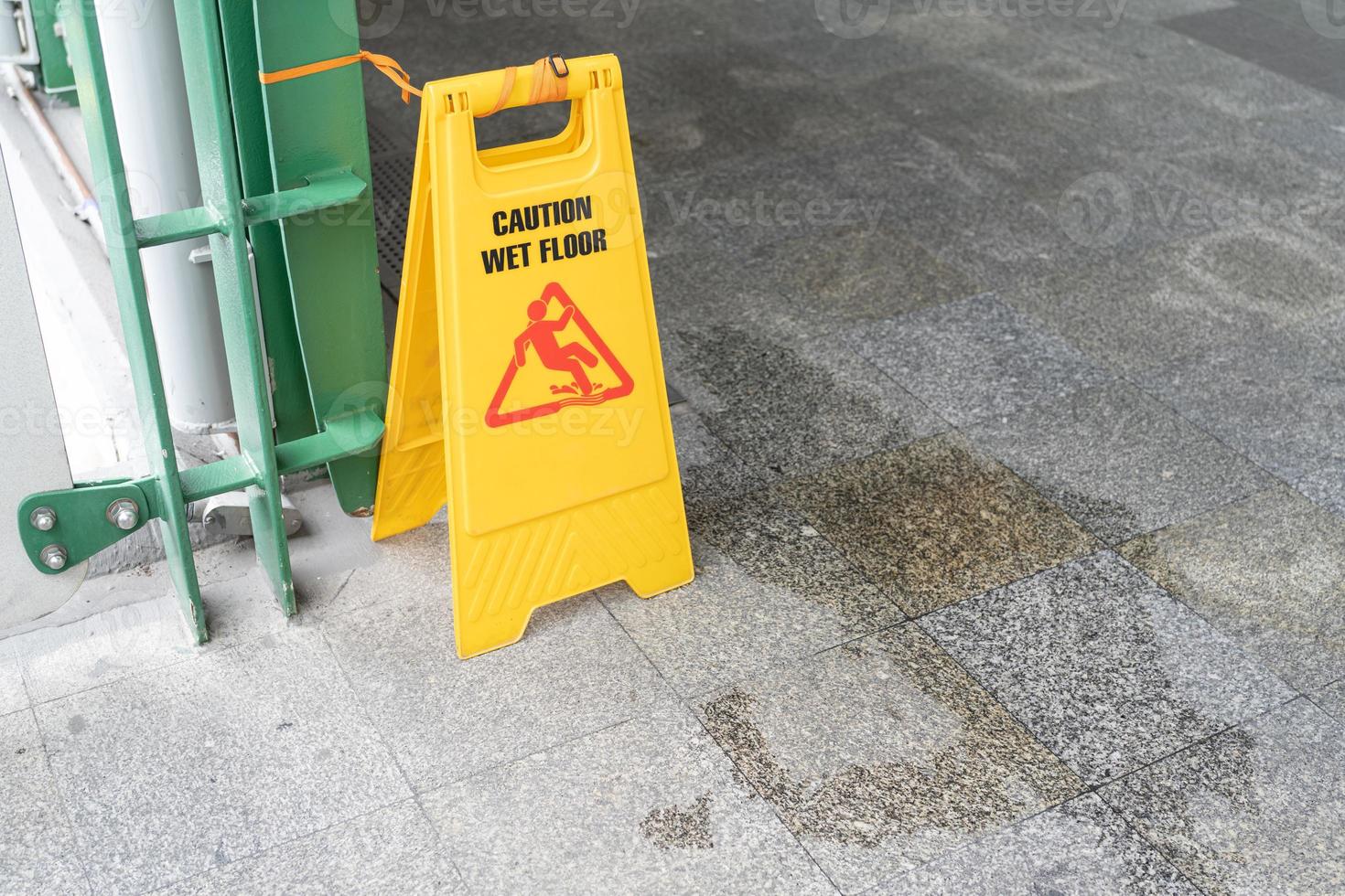 Yellow Caution slippery wet floor sign on the wet ground photo