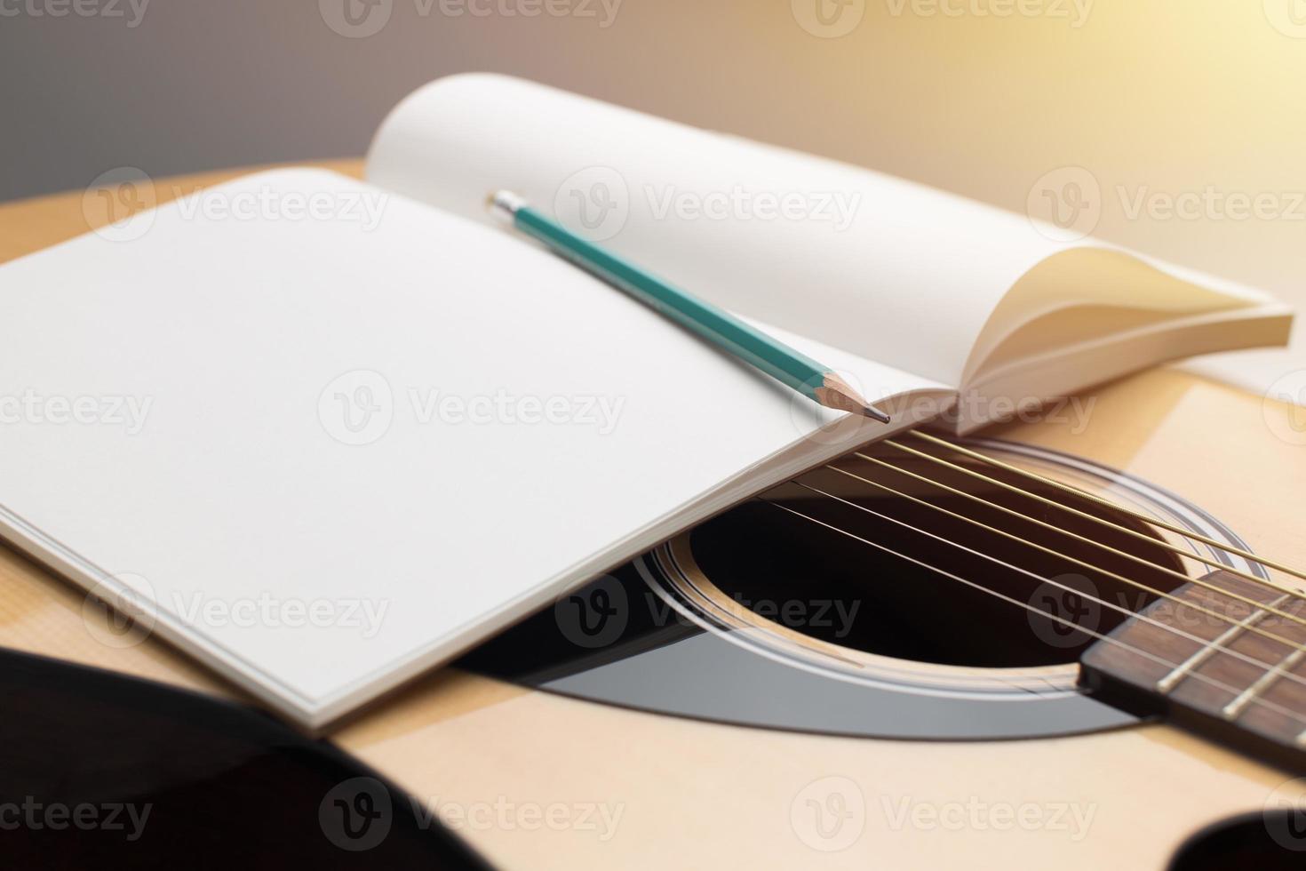componer música, lápiz y cuaderno colocados en guitarra acústica foto