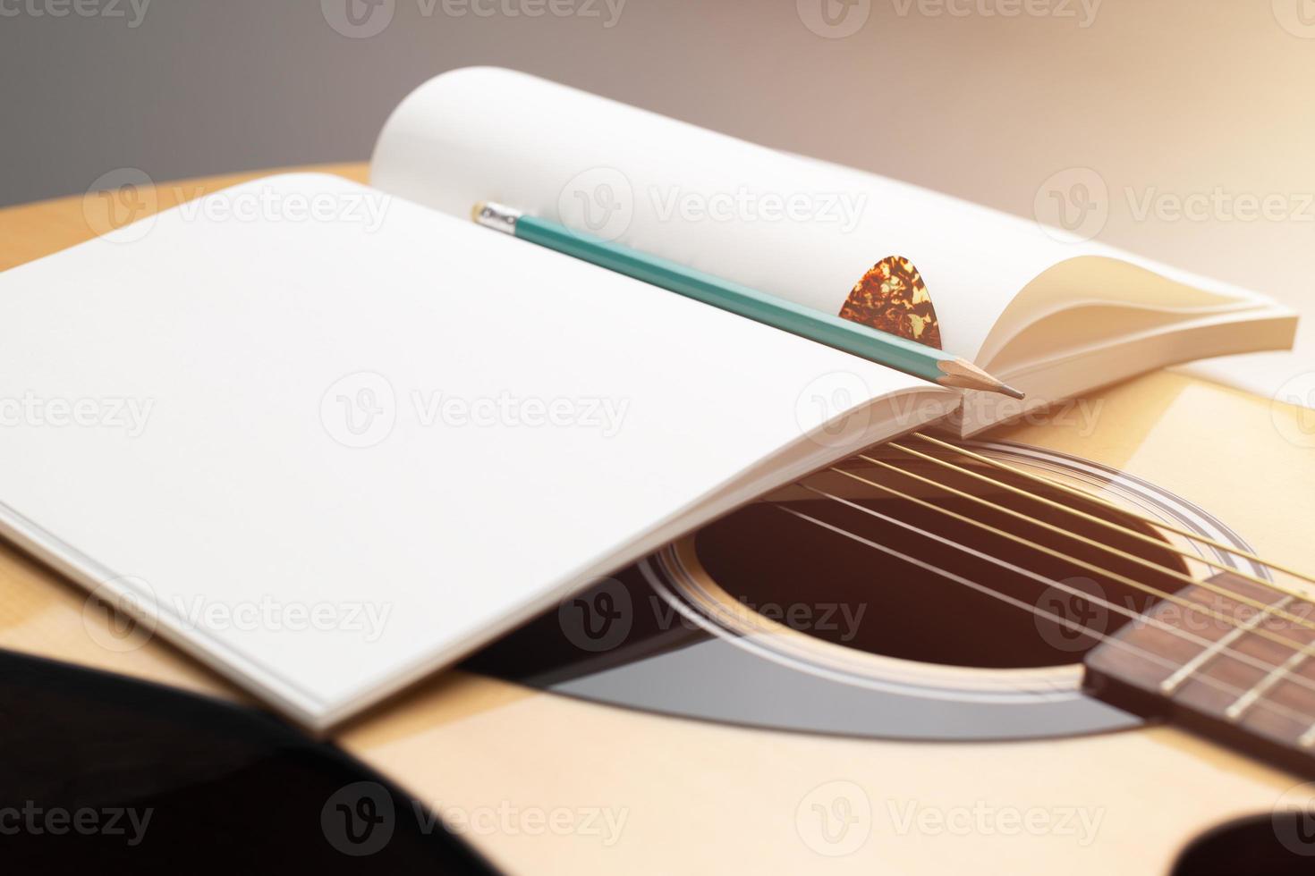 componer música. lápiz y cuaderno colocados en guitarra acústica foto