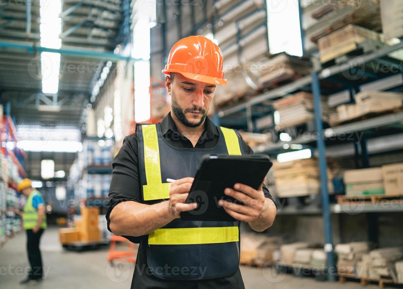 Professional manager man employee using tablet check stock working at warehouse. Worker wearing high visibility clothing and a hard hat, helmet and checking and count up goods or boxes for delivery. photo