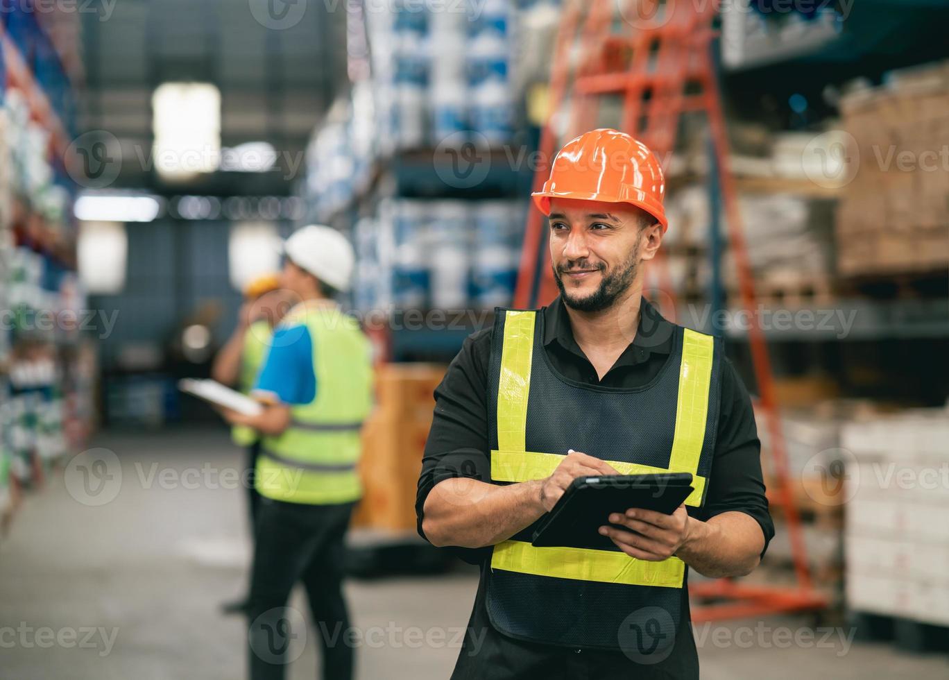 Professional manager man employee using tablet check stock working at warehouse. Worker wearing high visibility clothing and a hard hat, helmet and checking and count up goods or boxes for delivery. photo