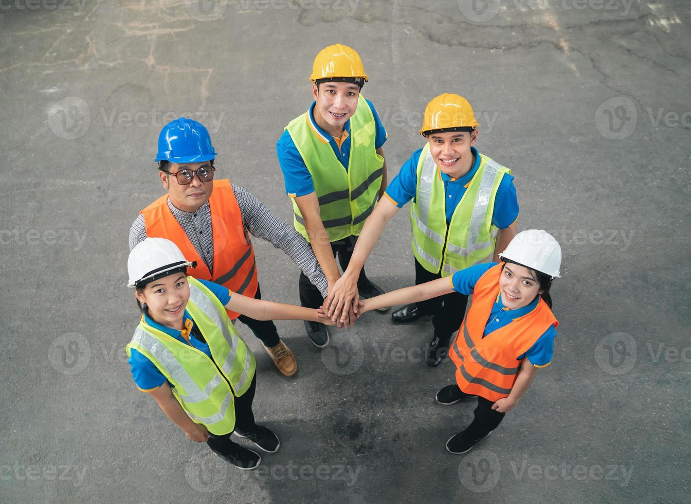 Group of industrial warehouse asian worker in and safety suite hand stack celebrate successful or deal commitment. Logistics , supply chain and warehouse business.Teamwork unity Top view concept. photo