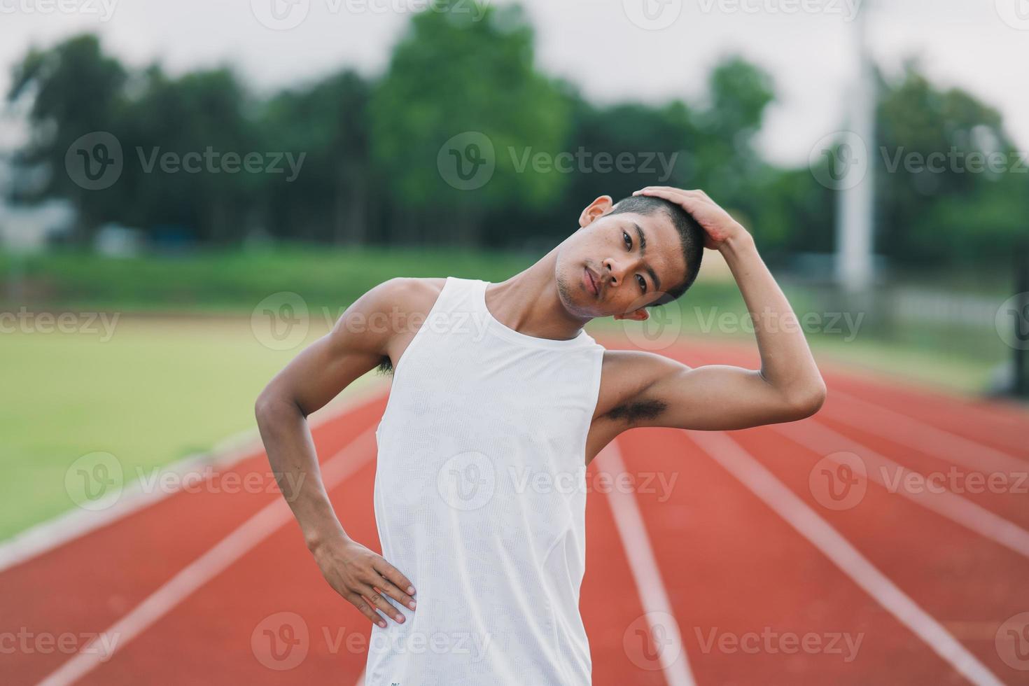 Athletes sport man runner wearing white sportswear to stretching and warm up before practicing on a running track at a stadium. Runner sport concept. photo