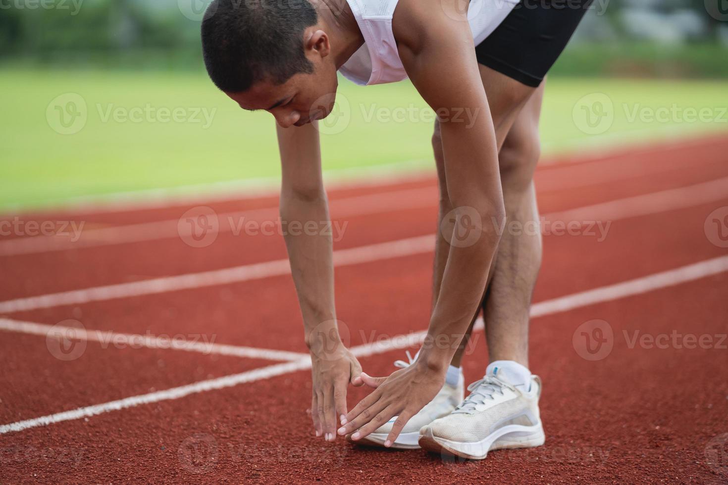 Athletes sport man runner wearing white sportswear to stretching and warm up before practicing on a running track at a stadium. Runner sport concept. photo