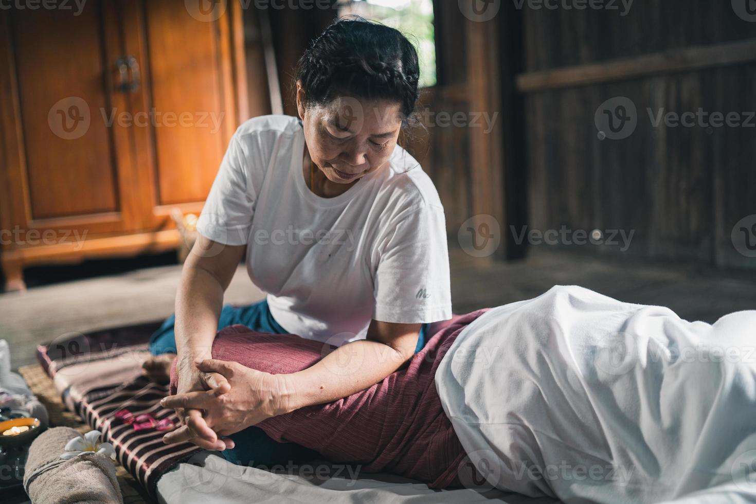 Massage and spa relaxing treatment of office syndrome traditional thai massage style. Asain senior female masseuse doing massage treat hand, back pain, arm pain, foot and stress for old woman tired. photo