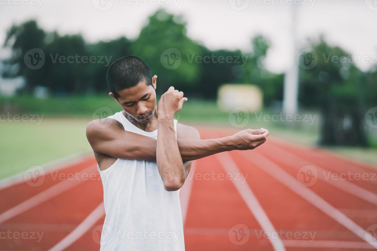 Athletes sport man runner wearing white sportswear to stretching and warm up before practicing on a running track at a stadium. Runner sport concept. photo
