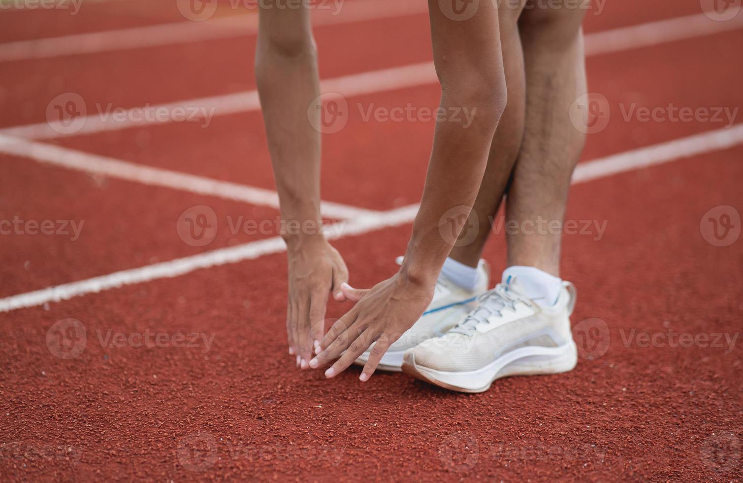 atletas deportistas corredores con ropa deportiva blanca para estirarse y calentarse antes de practicar en una pista de atletismo en un estadio. concepto de deporte de corredor. foto