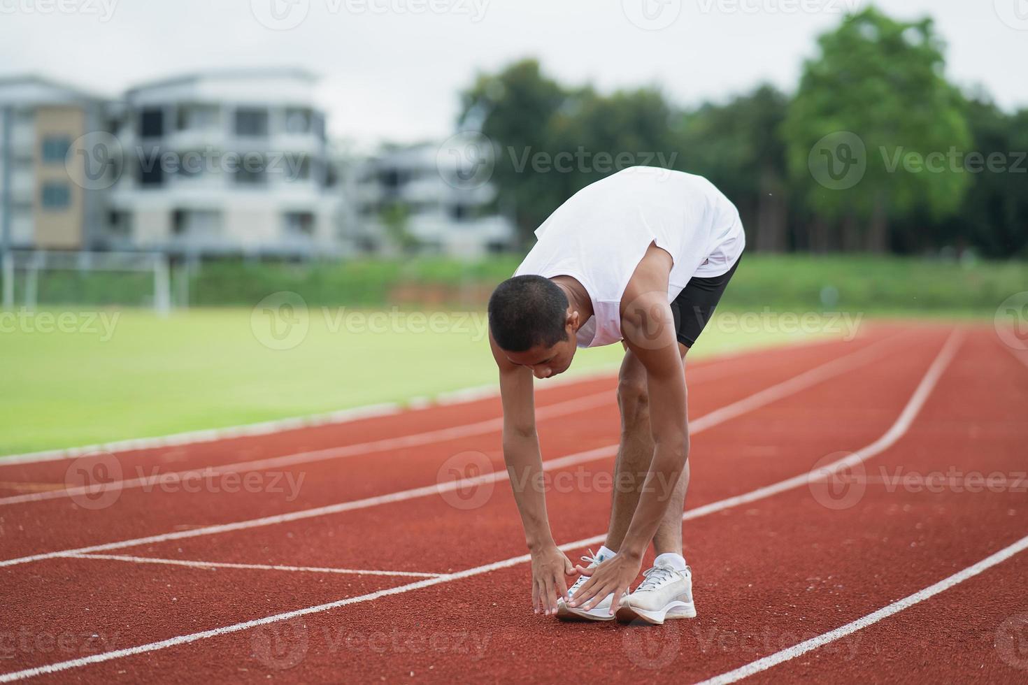 Athletes sport man runner wearing white sportswear to stretching and warm up before practicing on a running track at a stadium. Runner sport concept. photo