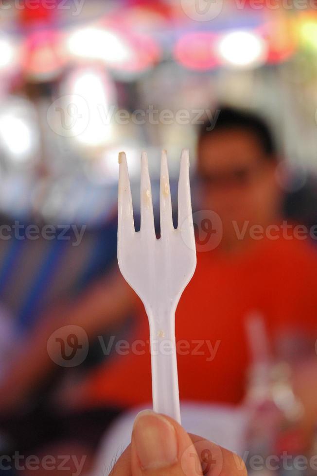 tenedor de plástico blanco sostenido por una mano foto