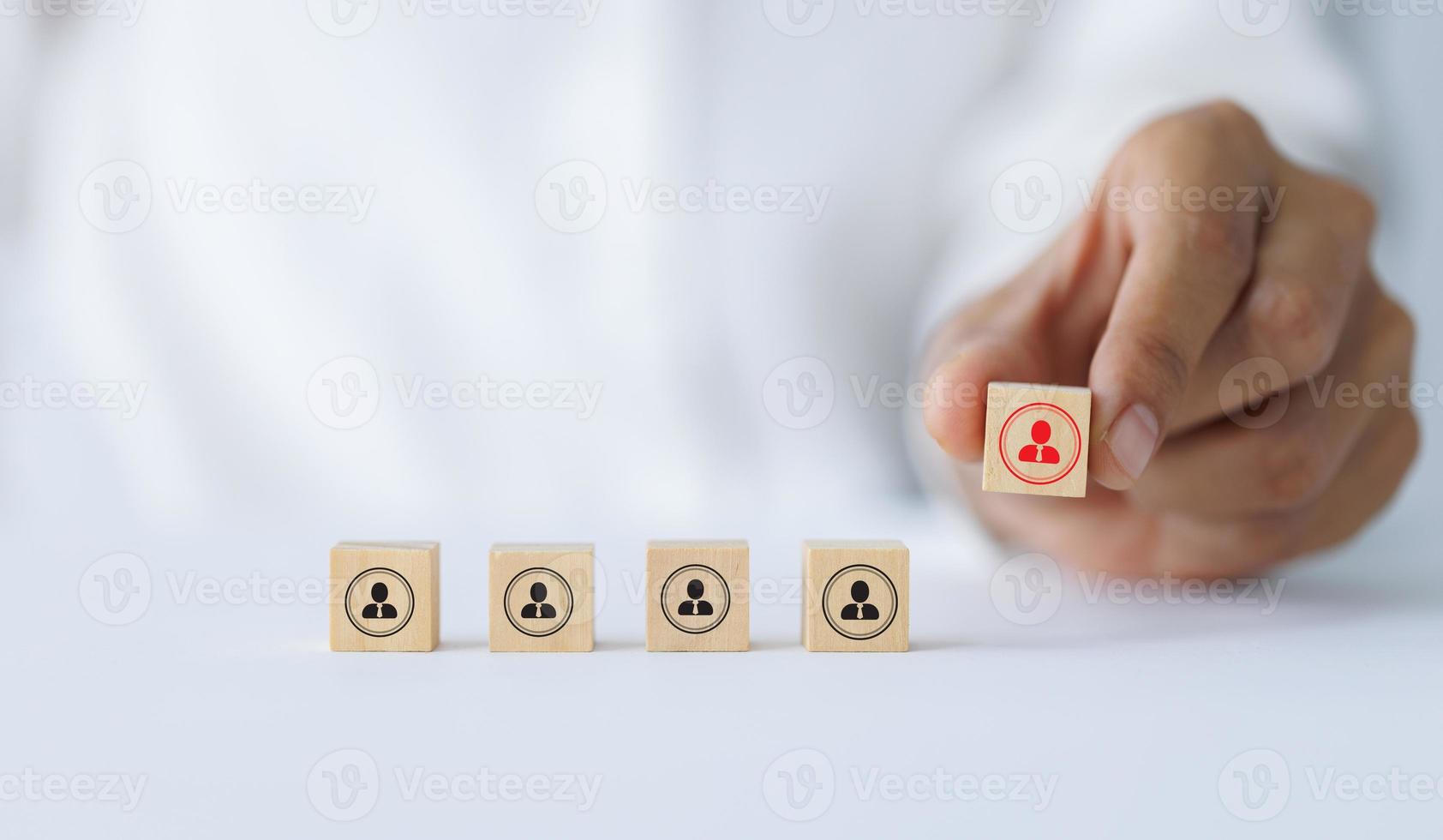 Hand holding a wooden block with people icon above mint square. Building a strong team, HR concept and management photo