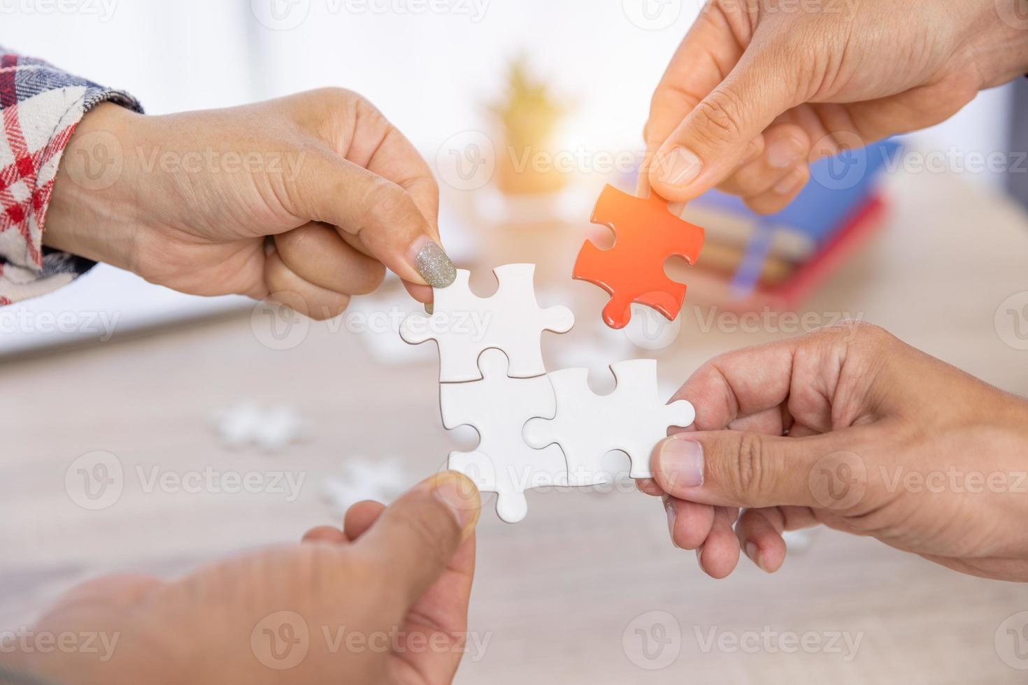 Businesspeople Hand Solving Jigsaw Puzzle On Wooden Desk, The concept of cooperation, teamwork, help and support in business. photo