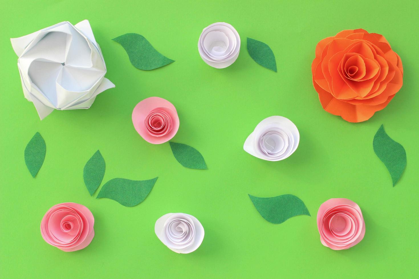 Origami paper colorful background with flowers and leaves on green background. Origami composition. Paper craft photo