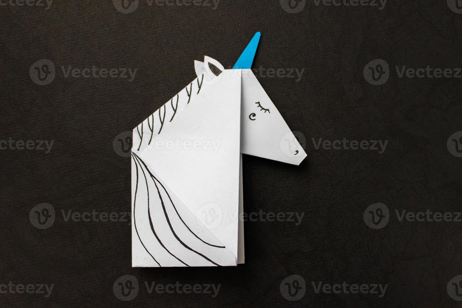 White unicorn made in the origami technique on black background. With place for your text. photo