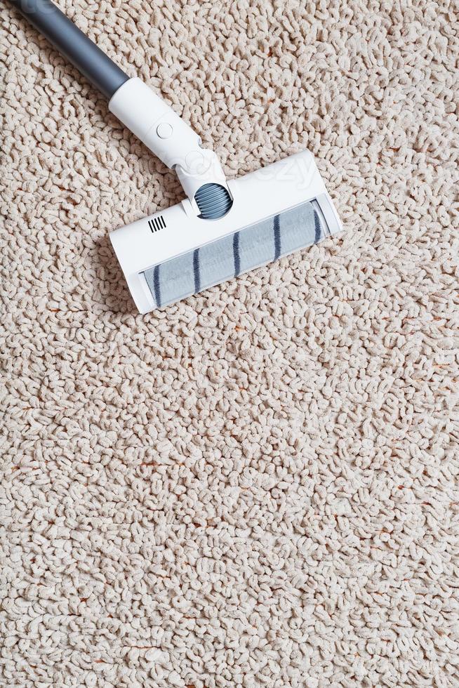 A white turbo brush of a cordless vacuum cleaner on the carpet. Indoor cleaning concept photo