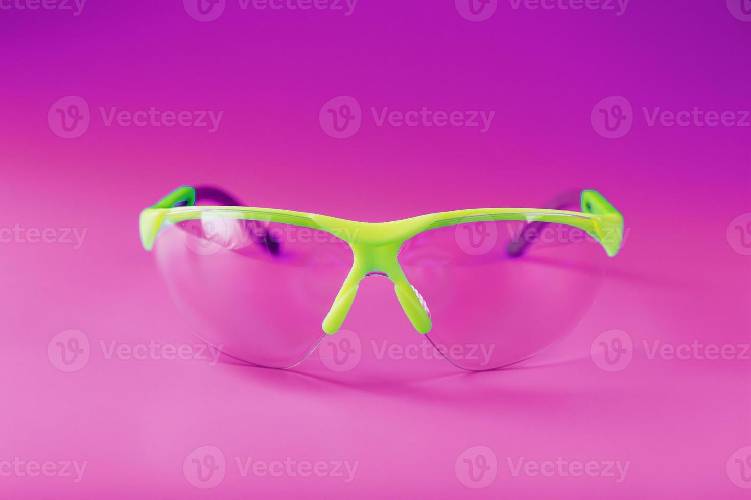 Transparent polycarbonate safety glasses on a pink background photo