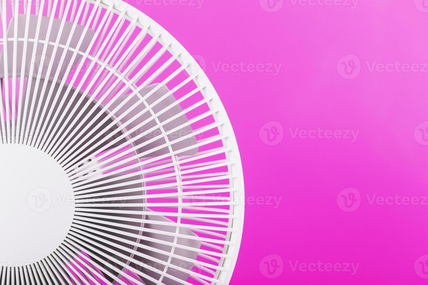 Electric fan in white with a modern design for cooling the room on a pink background. photo