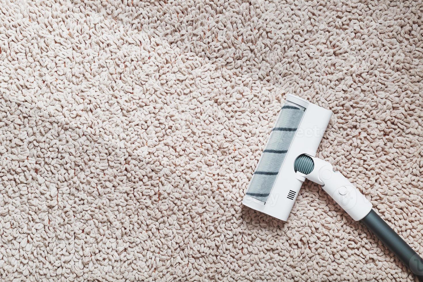 A white turbo brush of a cordless vacuum cleaner on the carpet. Indoor With a clean stripe photo