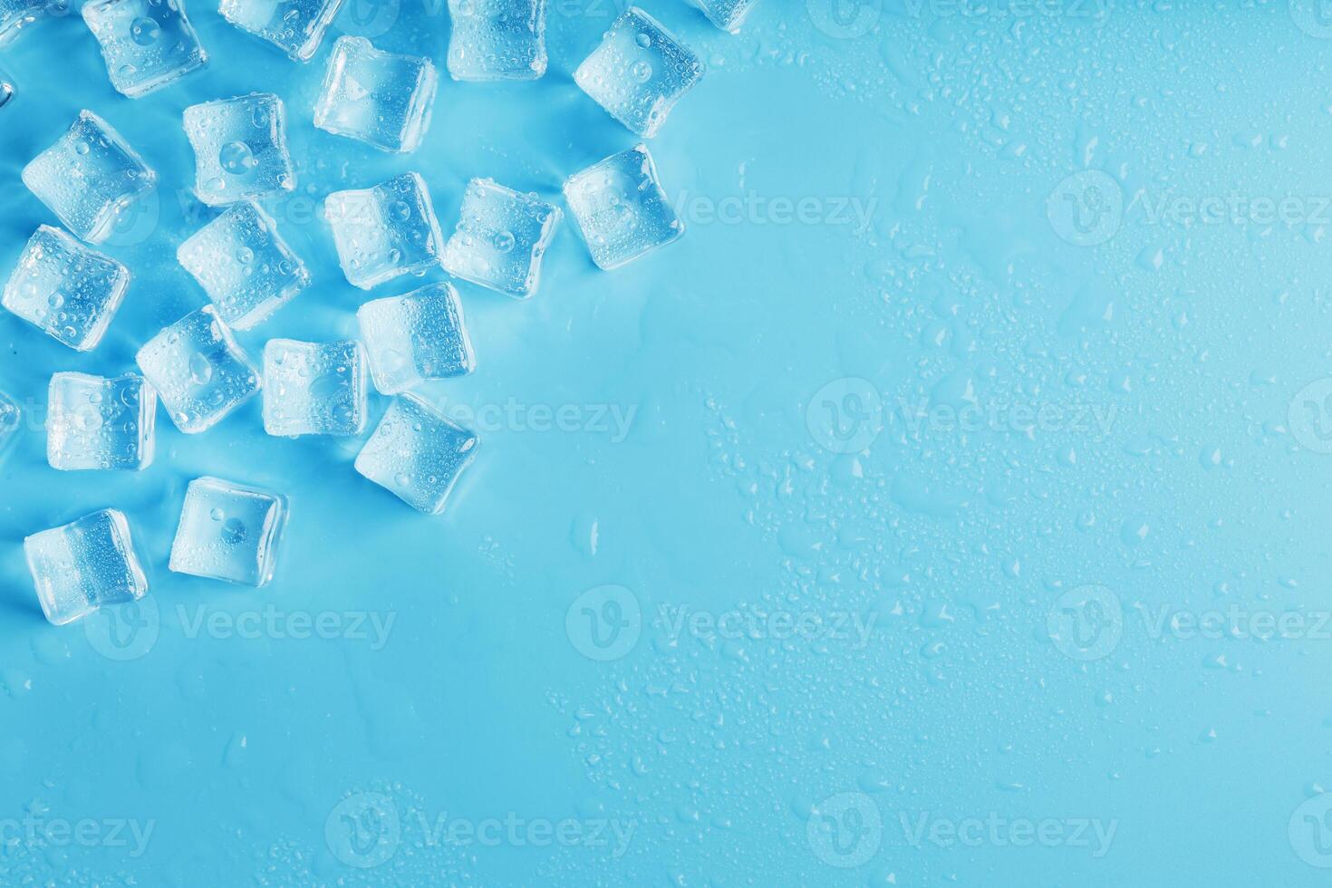 Ice made of cubes lined up with drops on a blue background with free