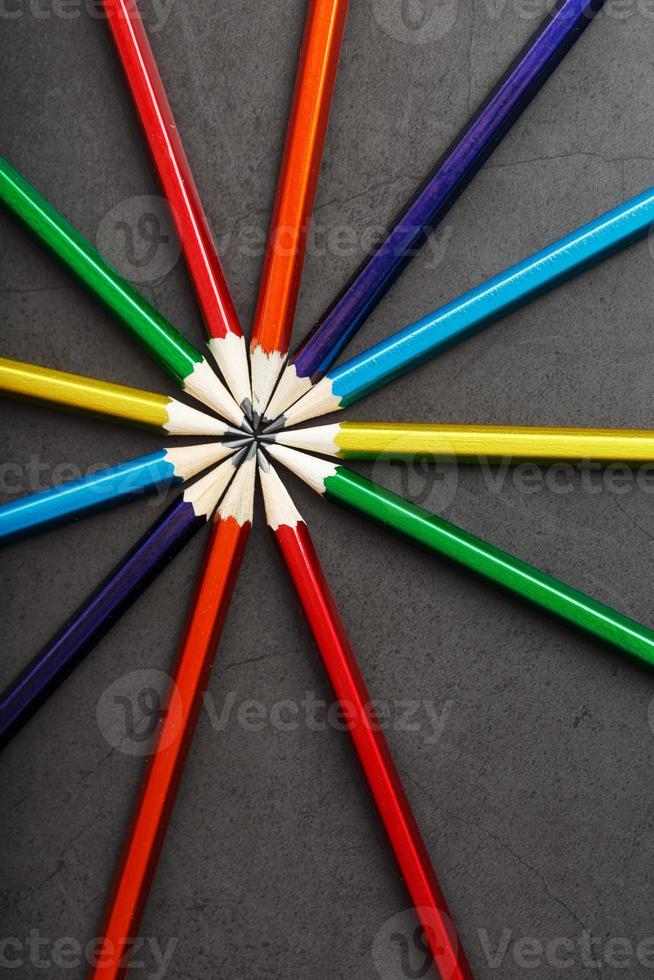 Wooden pencils of different colors in the shape of a star on a black background. photo