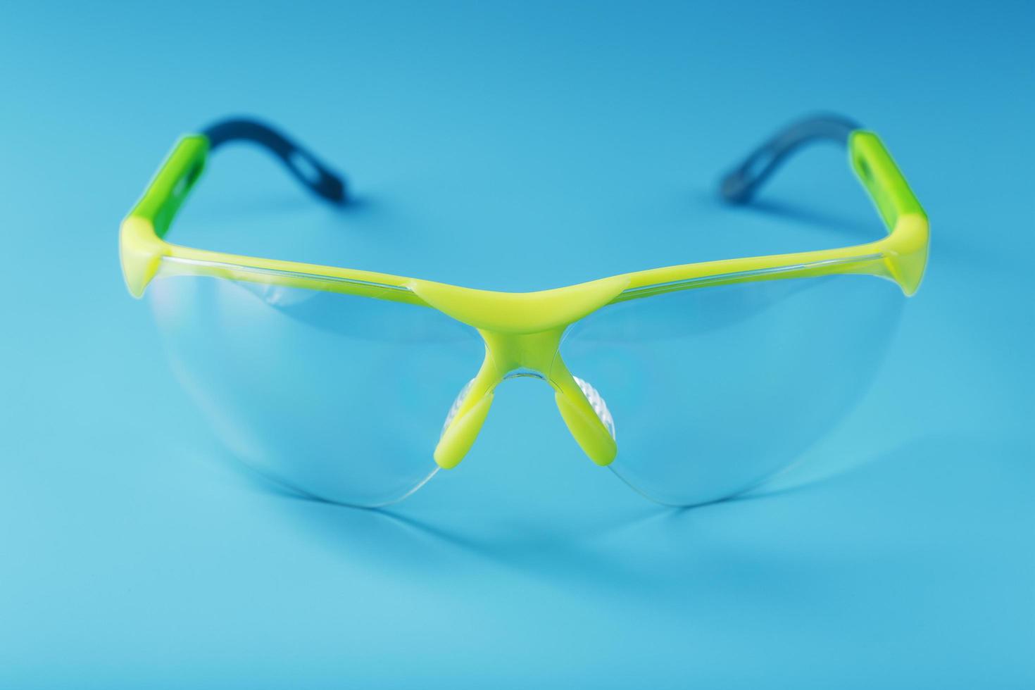 Transparent polycarbonate safety glasses on a blue background. photo
