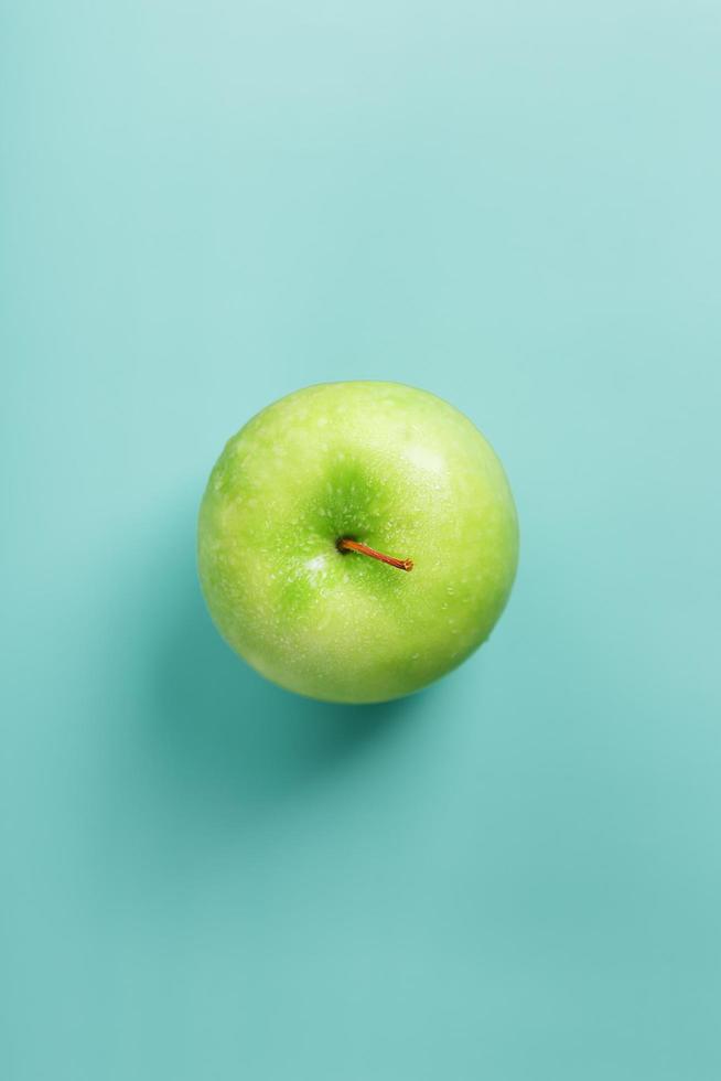 una manzana verde sobre un fondo verde con una composición minimalista. foto