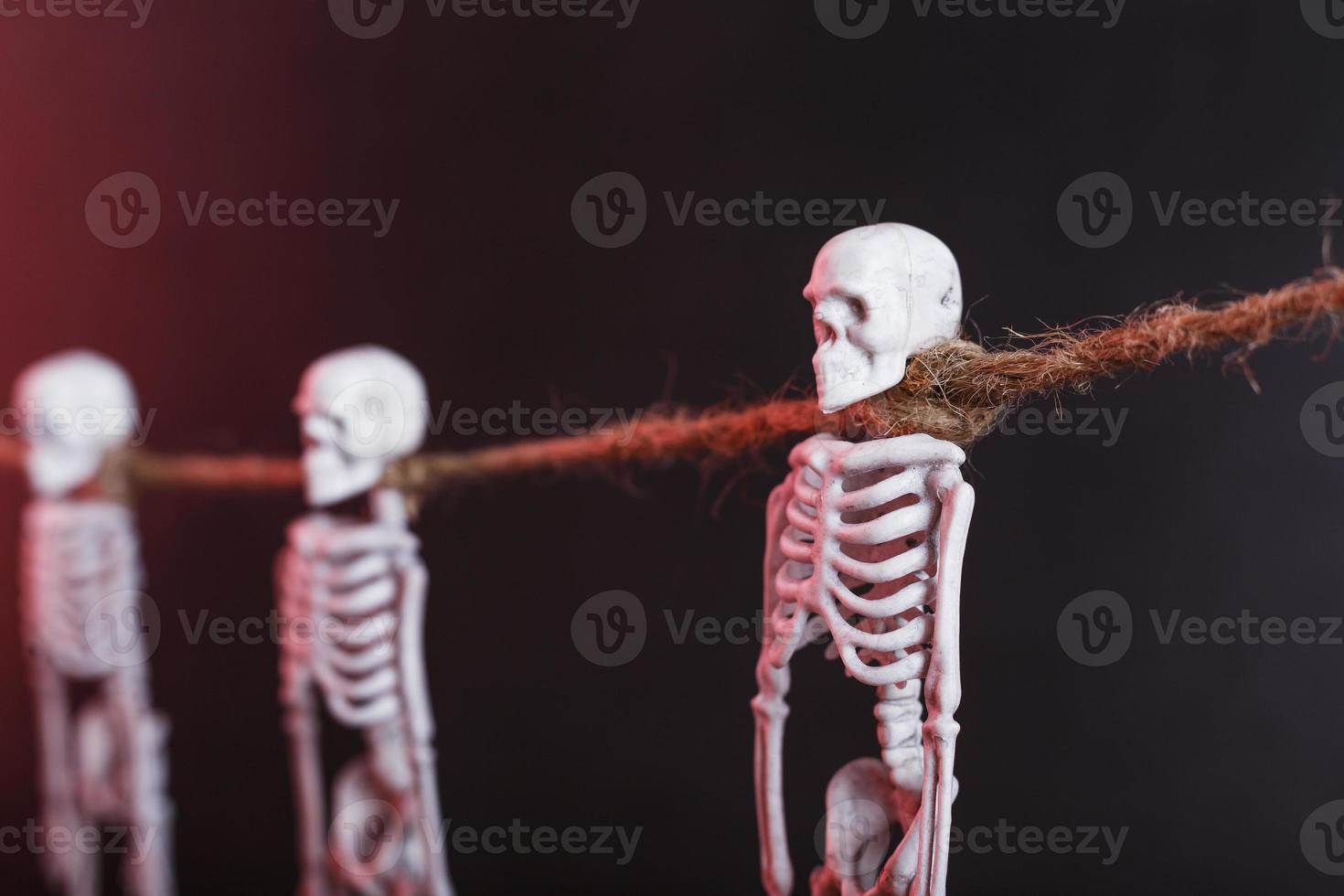 Skeletons hang on a rope on a black background with red illumination photo