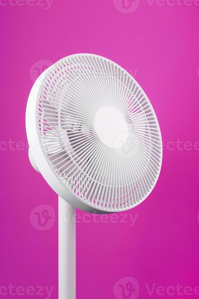 ventilador eléctrico en blanco con un diseño moderno para refrescar la habitación sobre un fondo rosa. foto