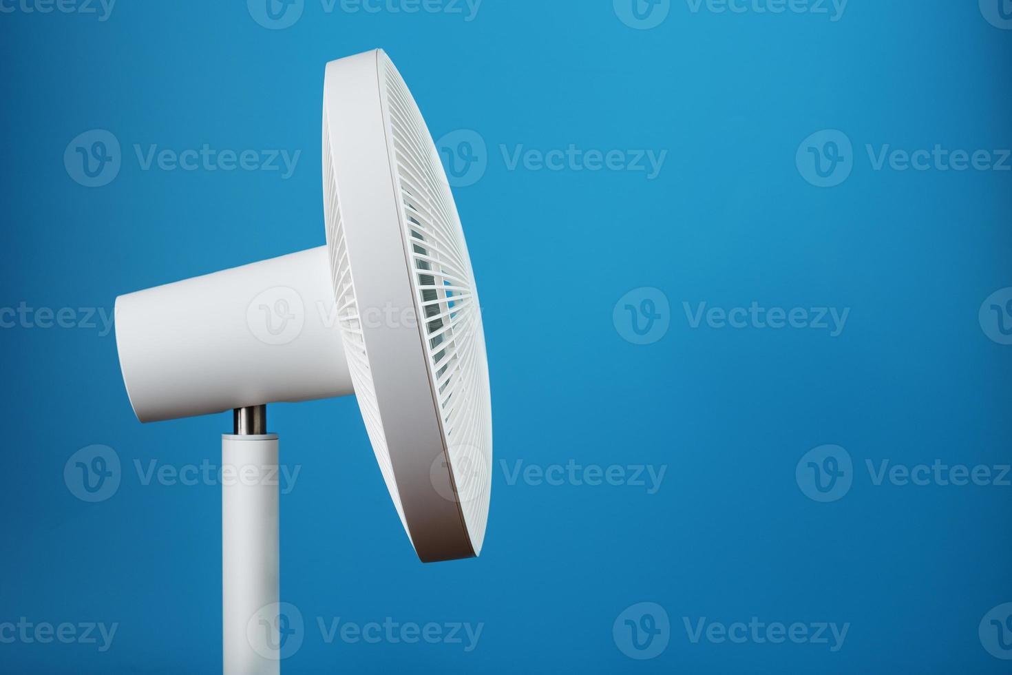 Electric fan in white with a modern design for cooling the room on a blue background photo