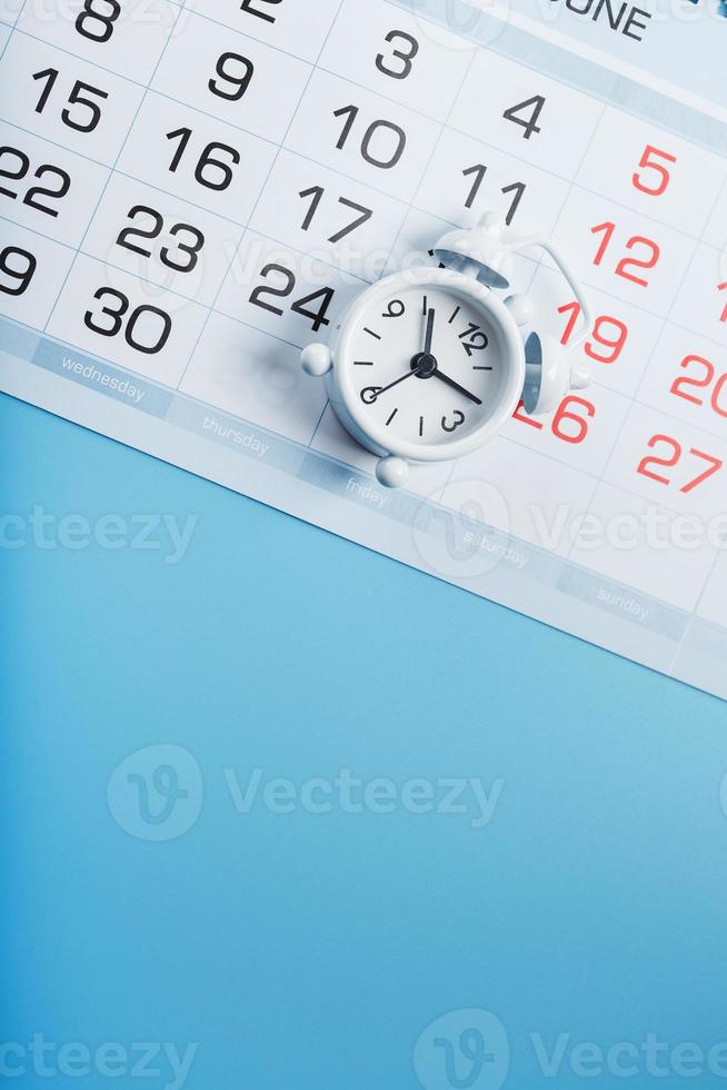 Alarm clock and calendar on a blue background photo