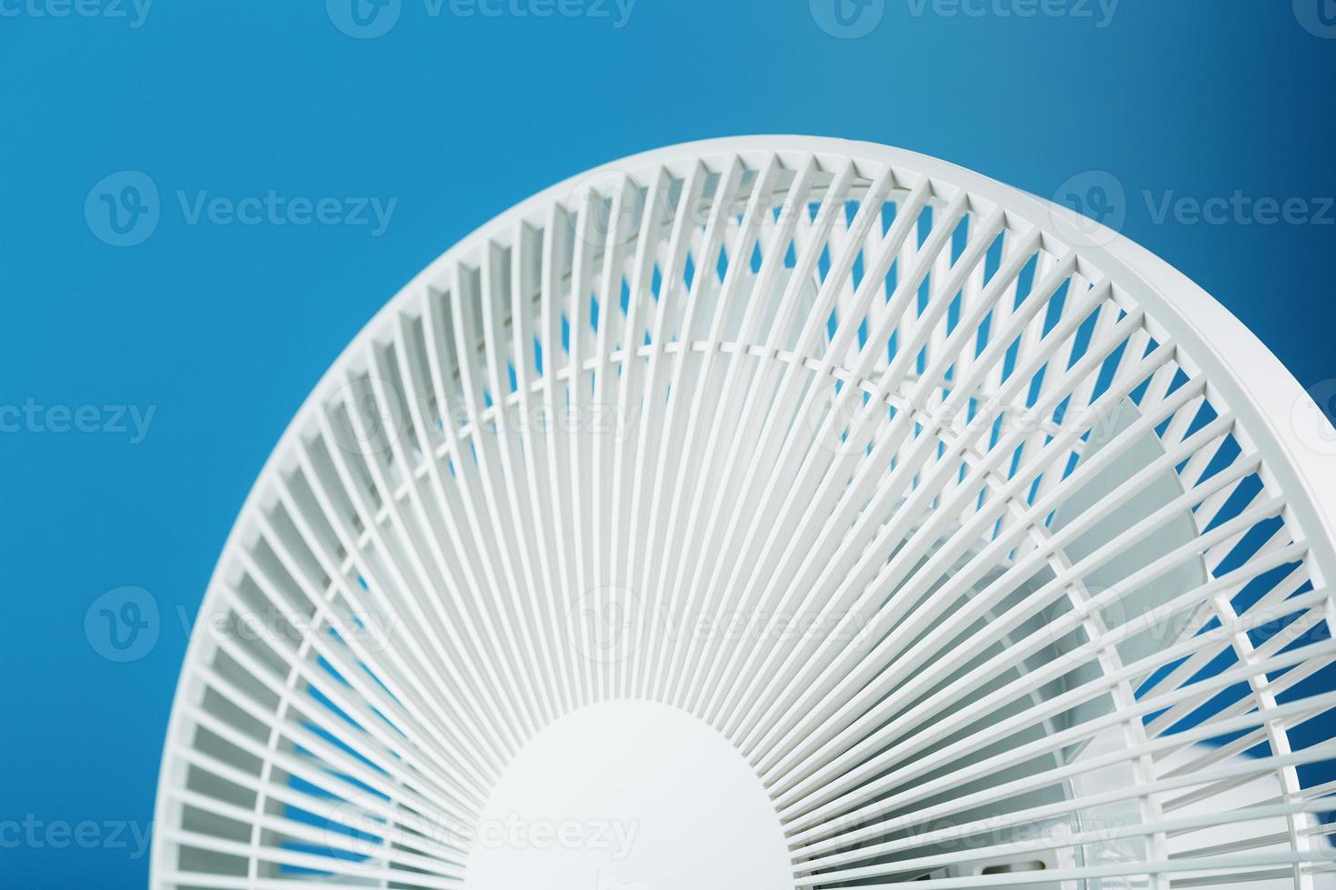 la rejilla y las aspas del ventilador eléctrico son blancas sobre un fondo azul foto