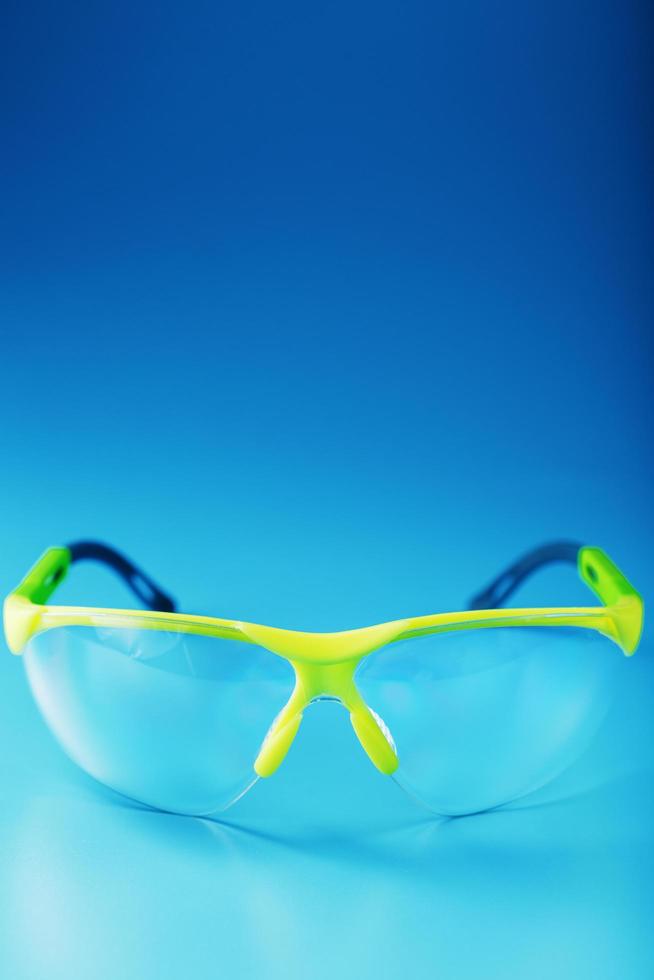 Technological protective green glasses isolated on a blue background. photo