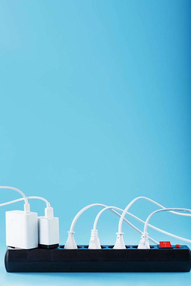 Electric mains filter with inserted white plugs of electrical appliances on a blue background. photo