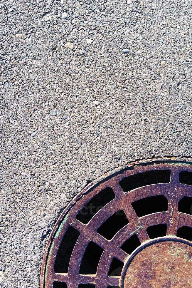 Part of a round manhole with grating on the asphalt. photo