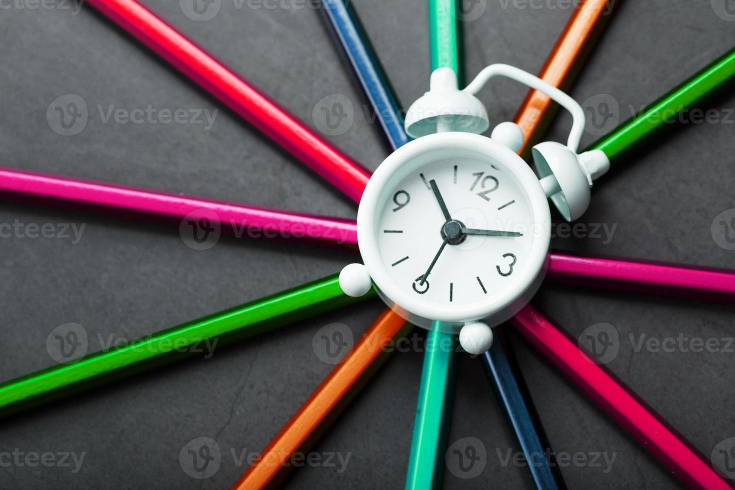 A white alarm clock with colored pencils in the shape of a star photo