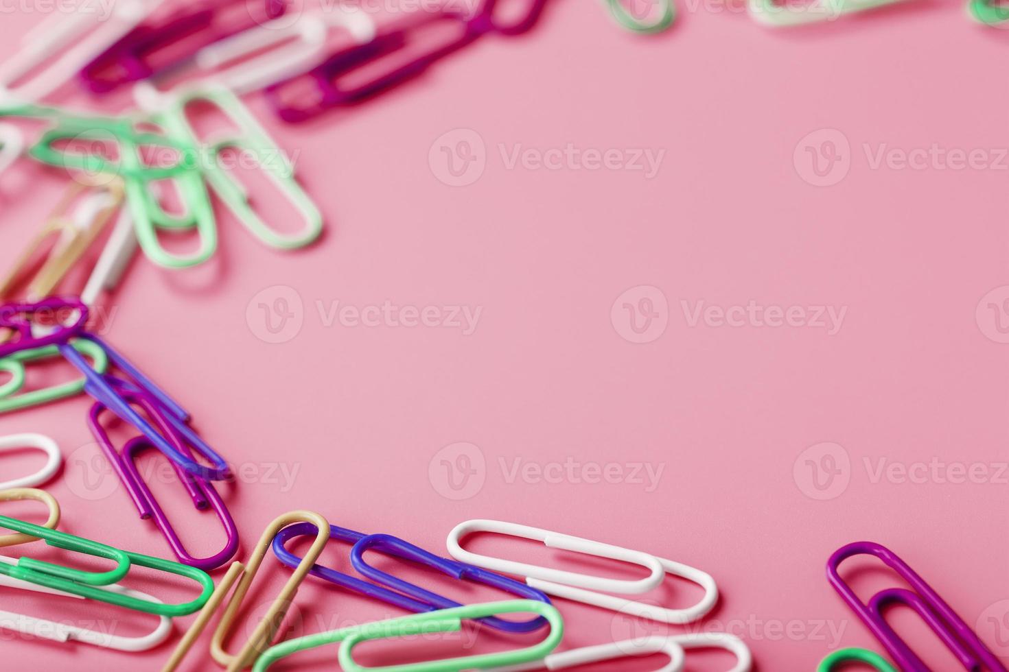 Multicolored rzhivtkzhtsrbt Paper clips scattered on a pink background photo