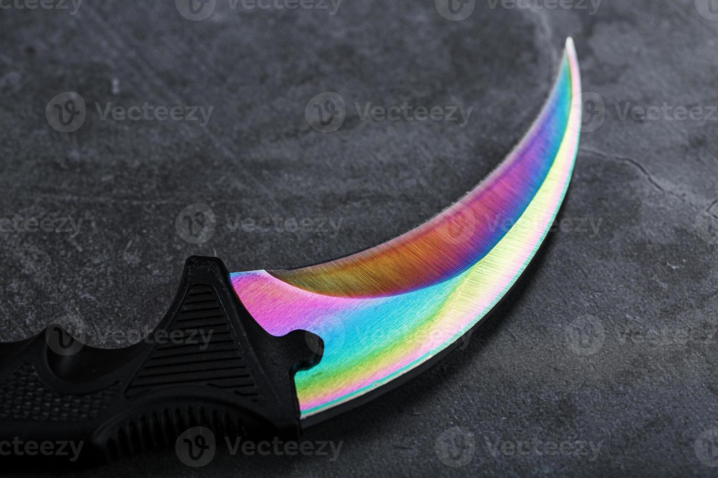 A dagger with a steel blade with a gradient color on a black background. photo
