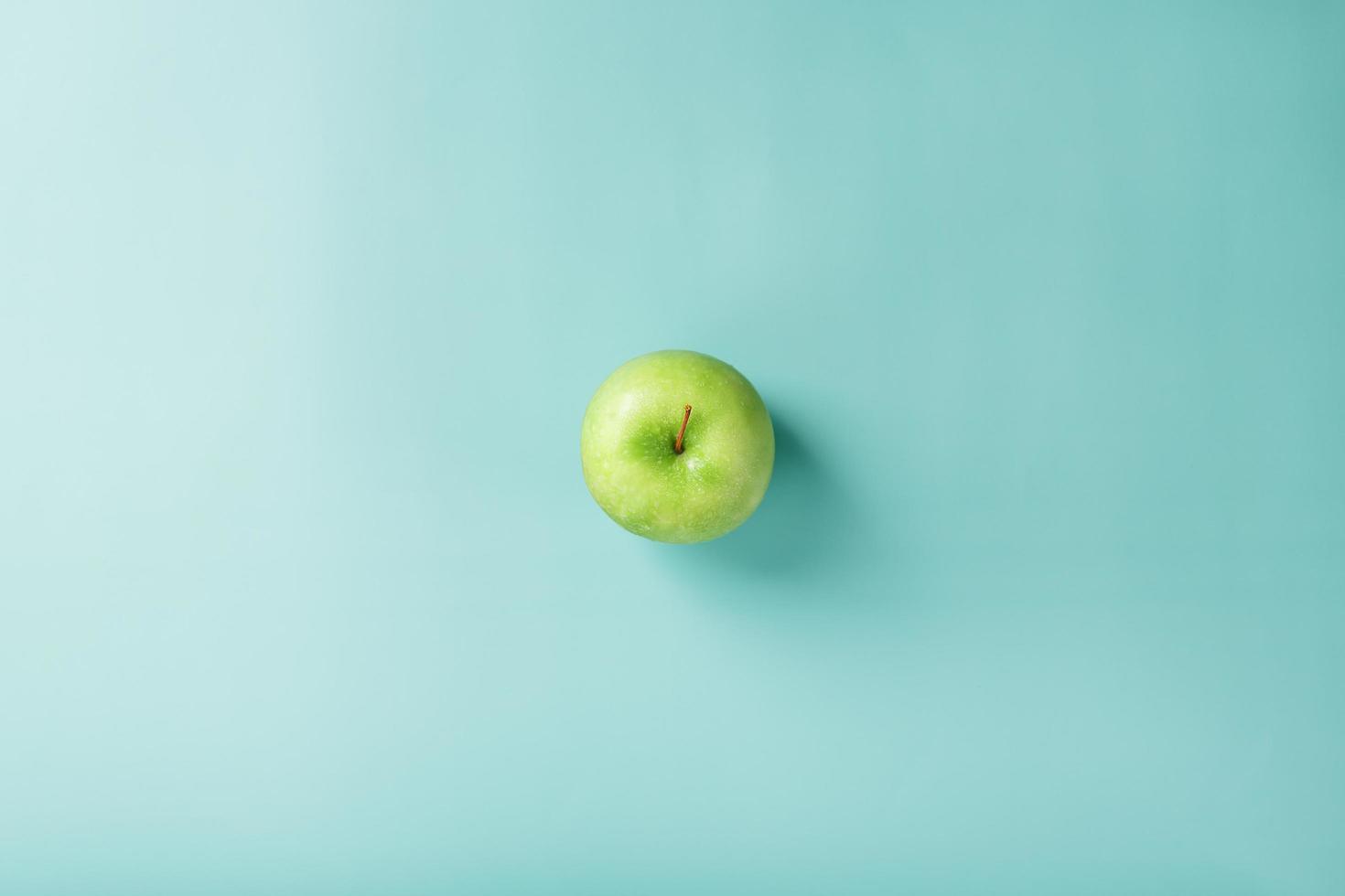 una manzana verde sobre un fondo verde con una composición minimalista. foto