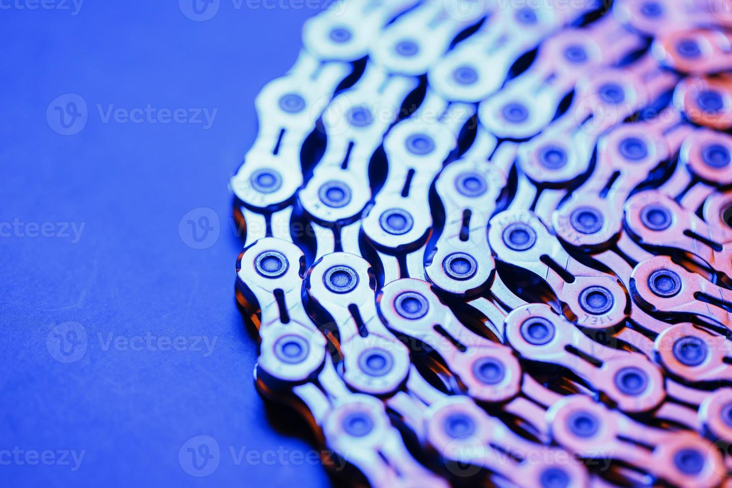 The texture of a shiny bicycle chain with a bluish-purple backlight photo