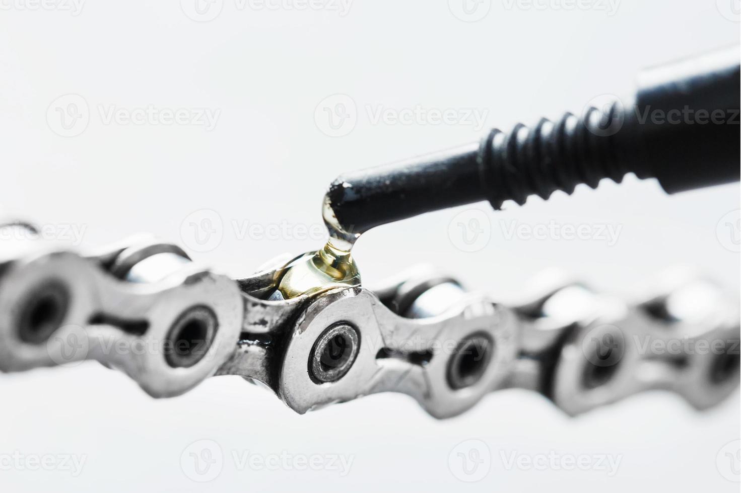 Lubricating a bicycle chain with a drop of oil close-up on an isolated gray background photo