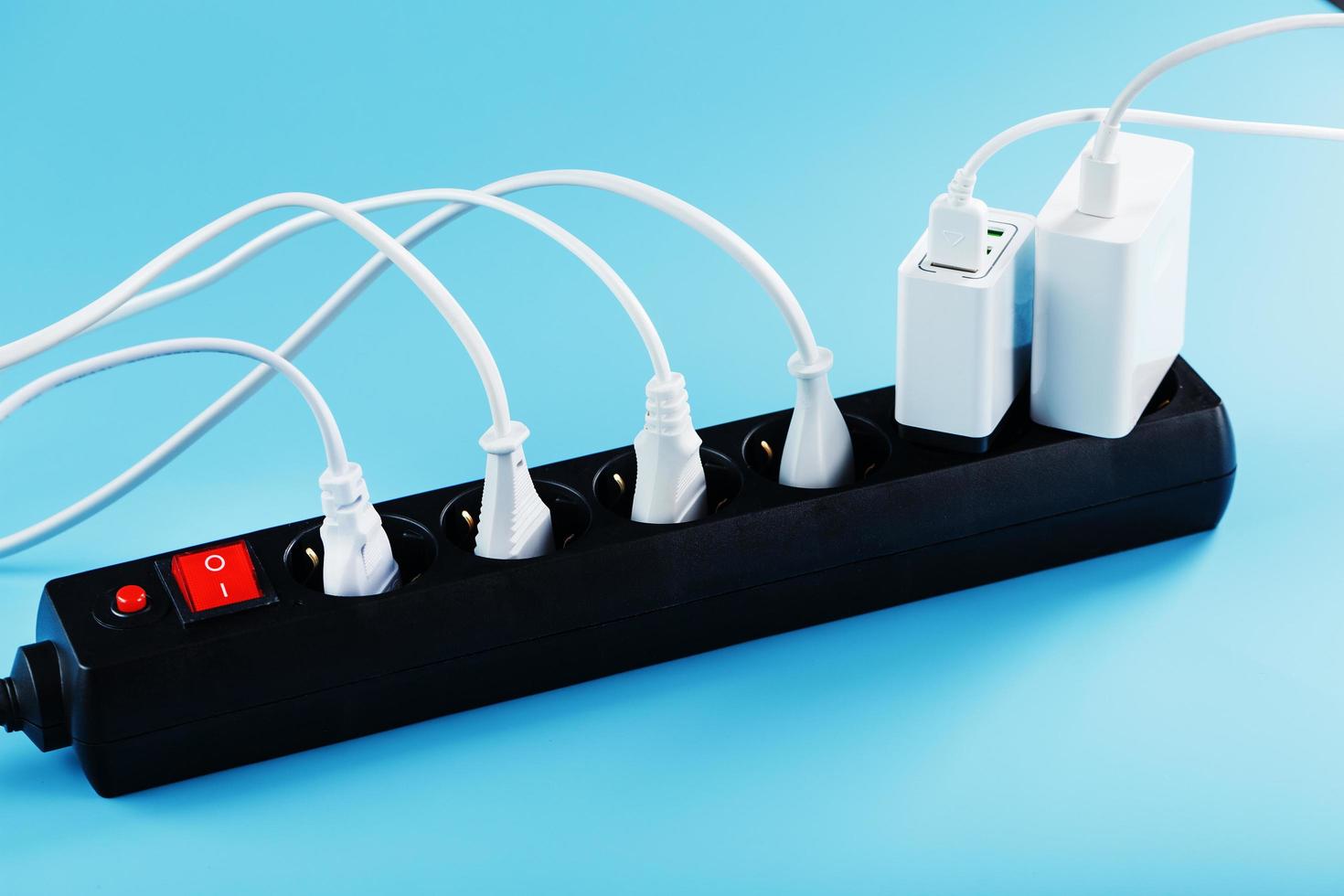 Surge protector with connected white wires of electrical appliances on a blue background. photo
