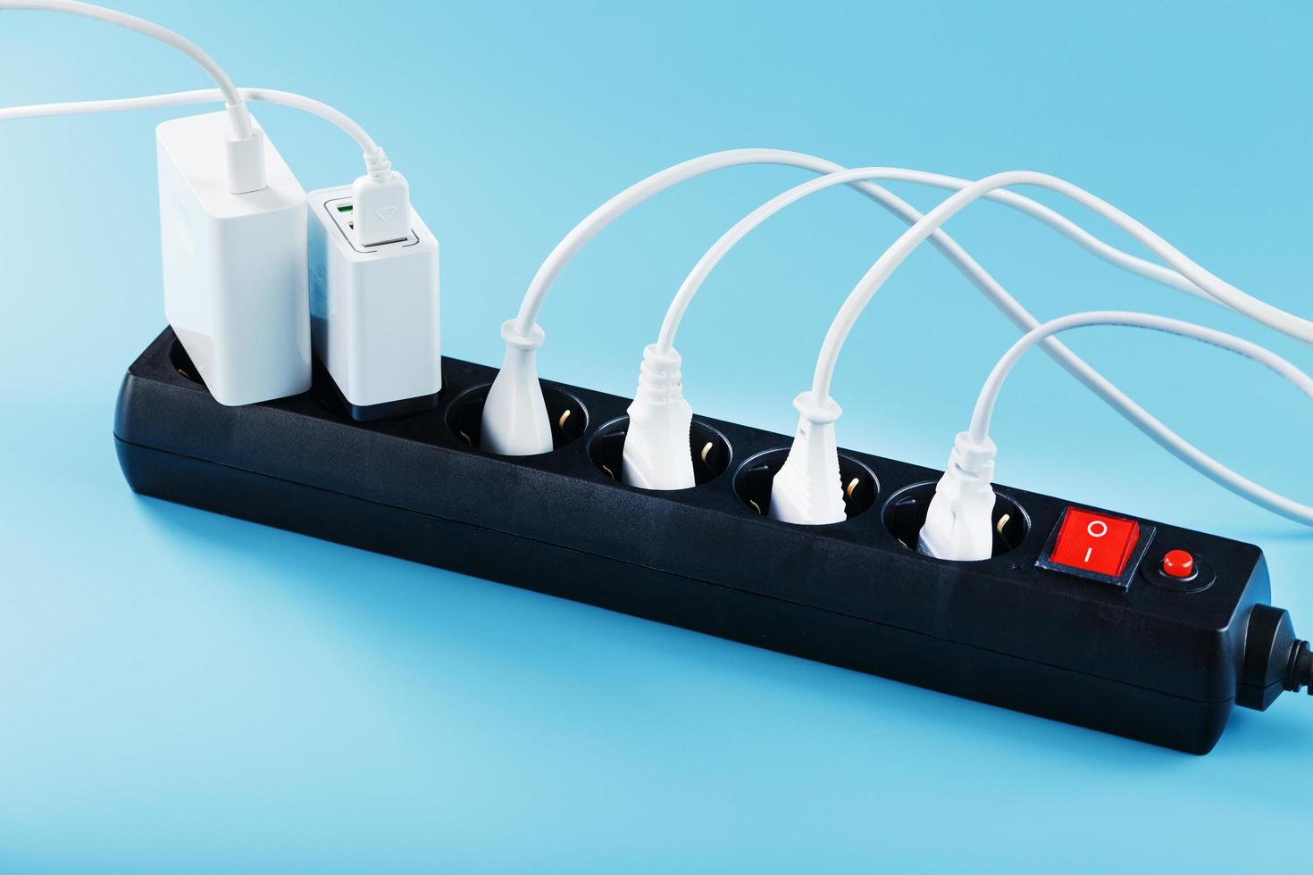 filtro de red eléctrica con enchufes blancos insertados de aparatos eléctricos sobre un fondo azul. foto