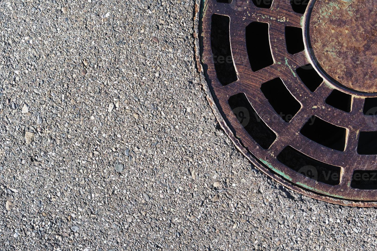 Sewer round hatch with a grate on an asphalt road. photo