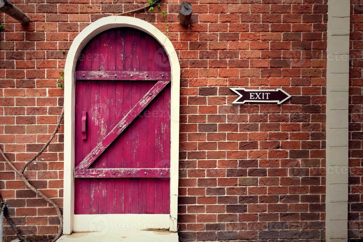 red vintage wooden door on brown brick wall photo