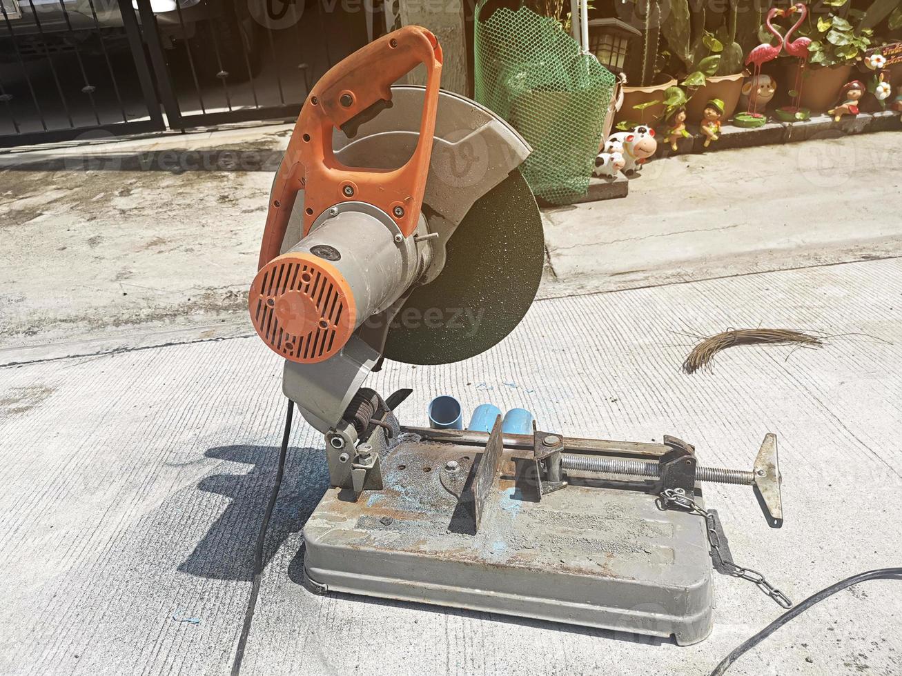 Old rusty sawing machine on the concrete floor at the house under construction. Electrical machinery for cutting hard materials photo